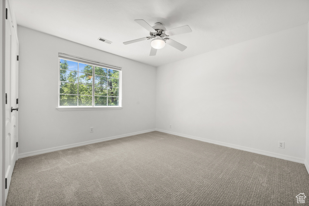 Carpeted spare room featuring baseboards and a ceiling fan