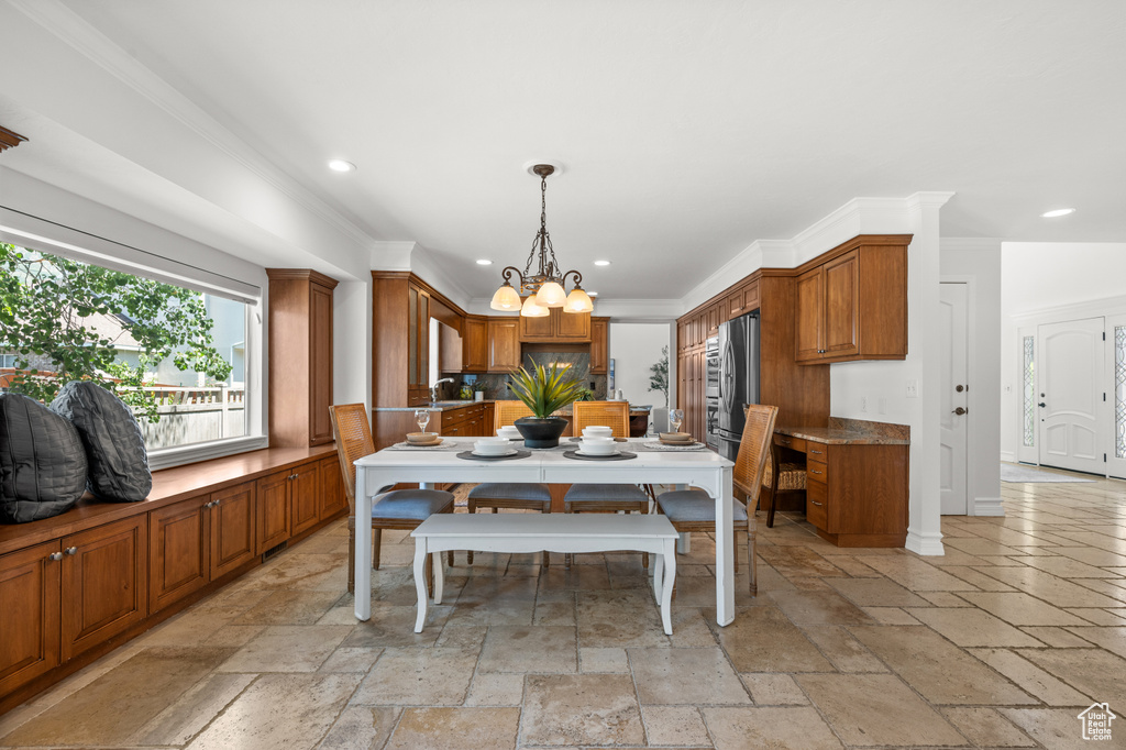 Dining room with stone tile flooring, recessed lighting, a chandelier, and ornamental molding