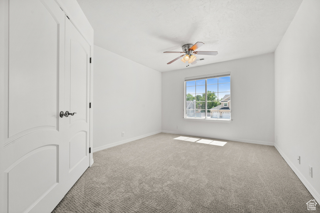 Carpeted spare room featuring a ceiling fan and baseboards