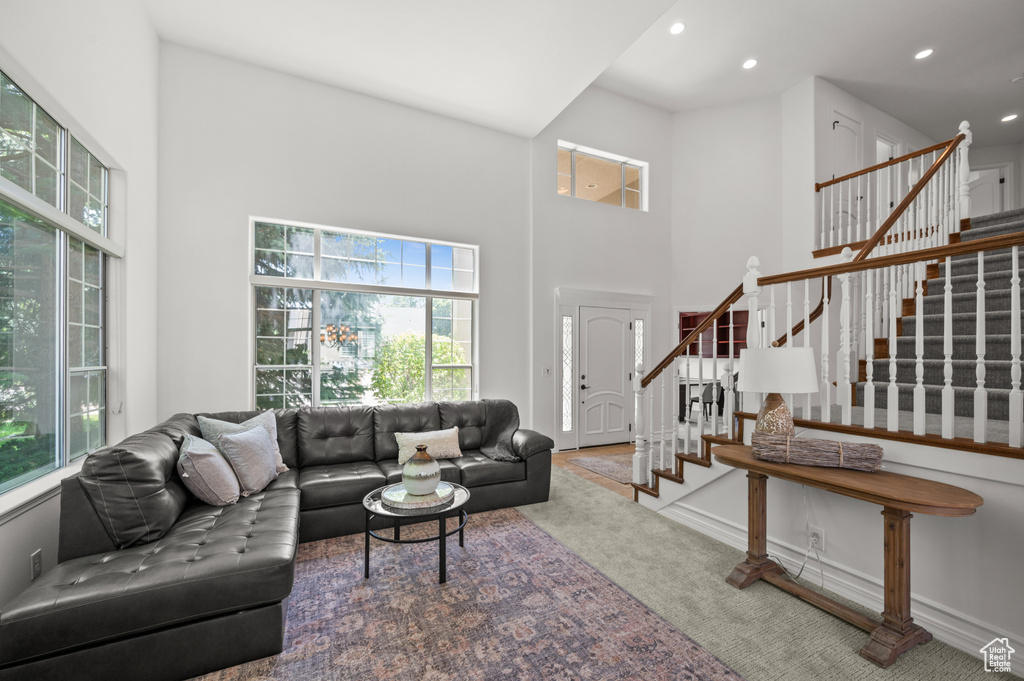 Living area with a high ceiling, plenty of natural light, stairway, carpet floors, and recessed lighting