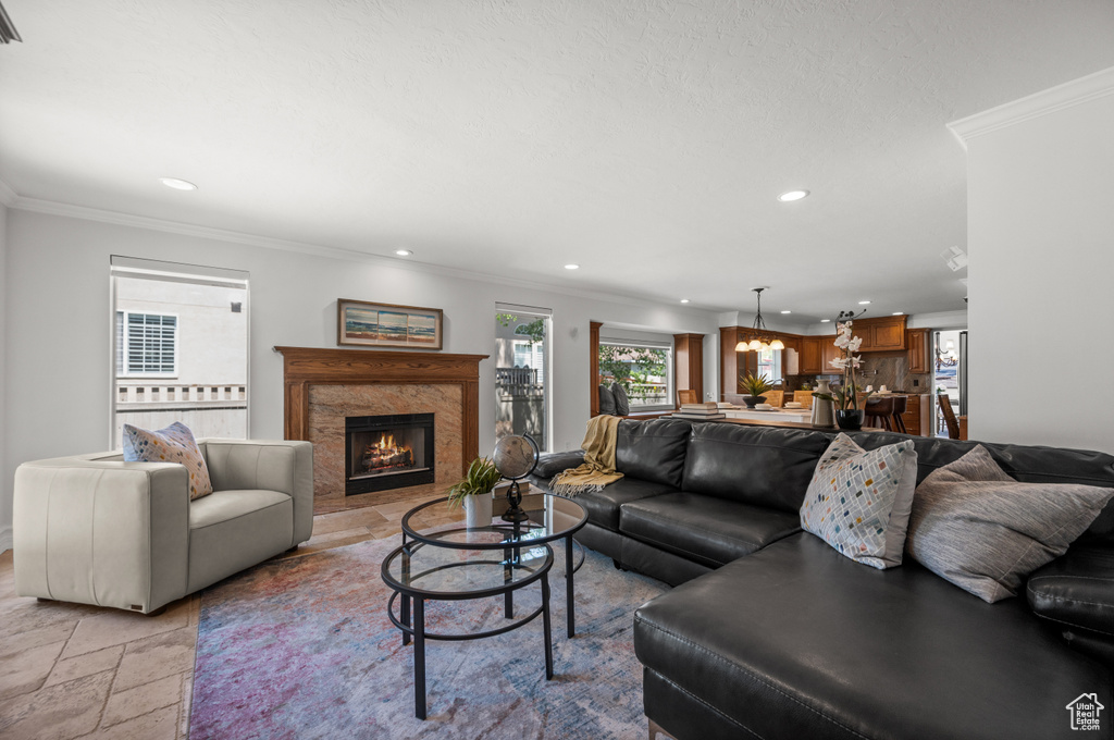 Living area with recessed lighting, crown molding, a premium fireplace, and stone tile flooring