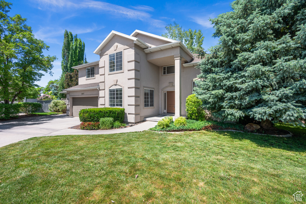 View of front of property featuring concrete driveway, an attached garage, stucco siding, and a front lawn