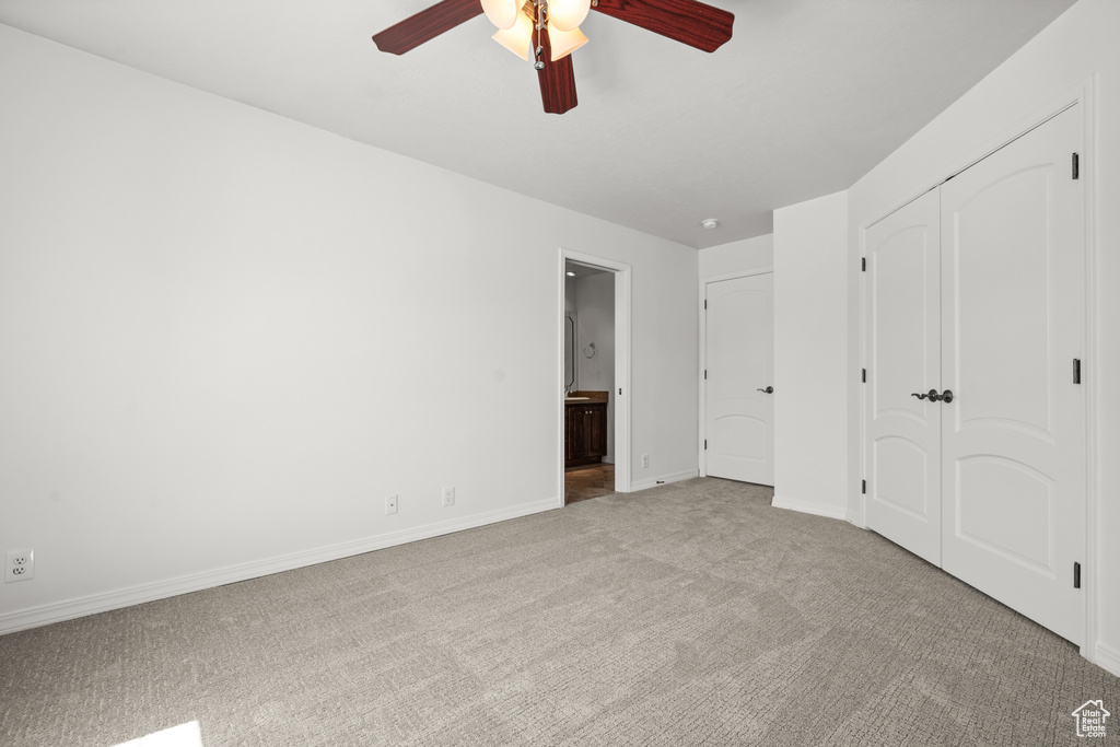 Unfurnished bedroom featuring carpet, baseboards, connected bathroom, a closet, and a ceiling fan