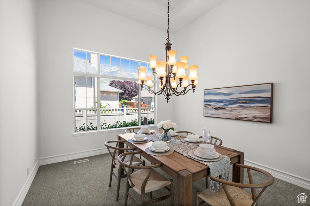 Carpeted dining space with a chandelier, a towering ceiling, and baseboards