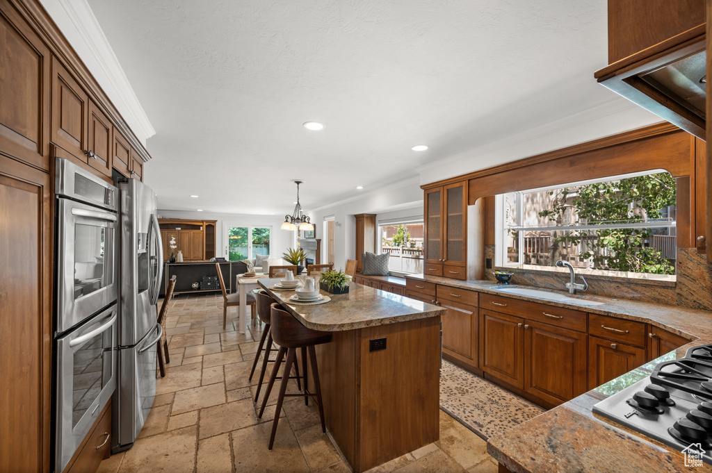 Kitchen with stone tile floors, a sink, appliances with stainless steel finishes, a kitchen island, and recessed lighting