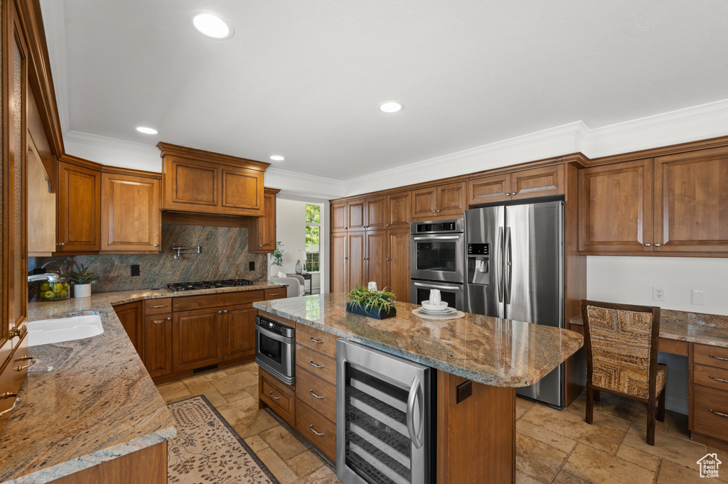 Kitchen with stainless steel appliances, beverage cooler, stone tile floors, ornamental molding, and brown cabinetry