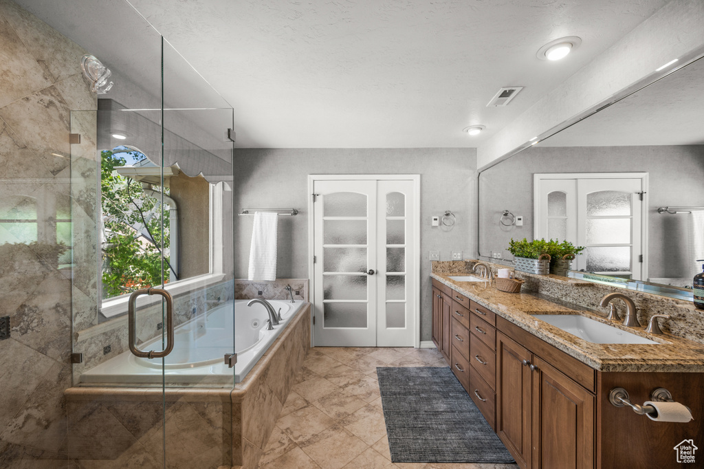Bathroom with double vanity, a bath, a stall shower, and french doors