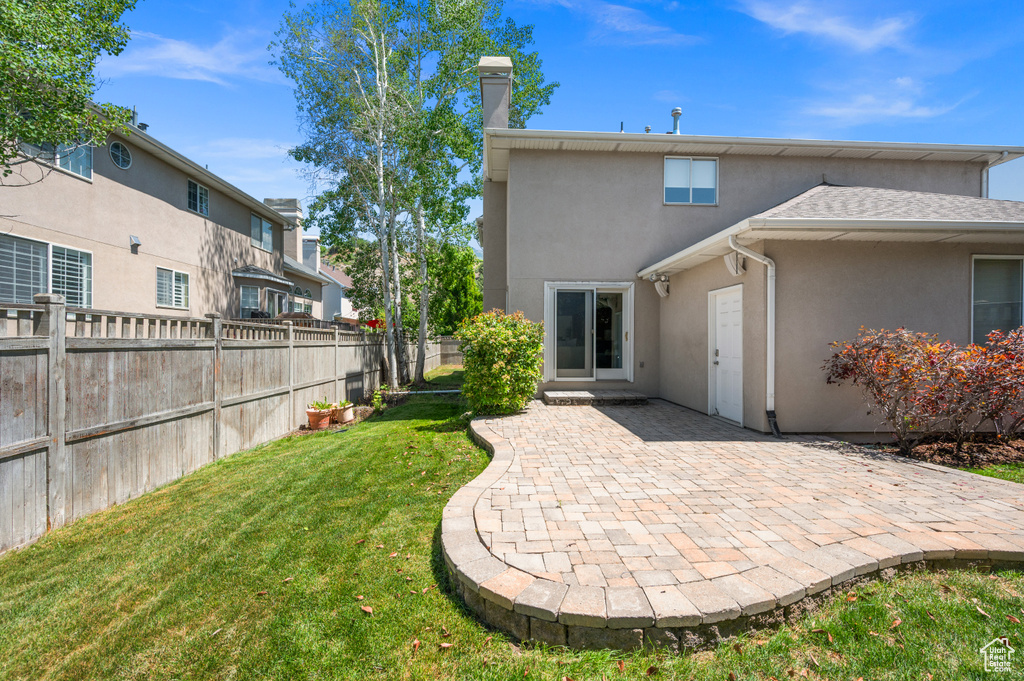 Back of house featuring stucco siding, a patio, and a chimney