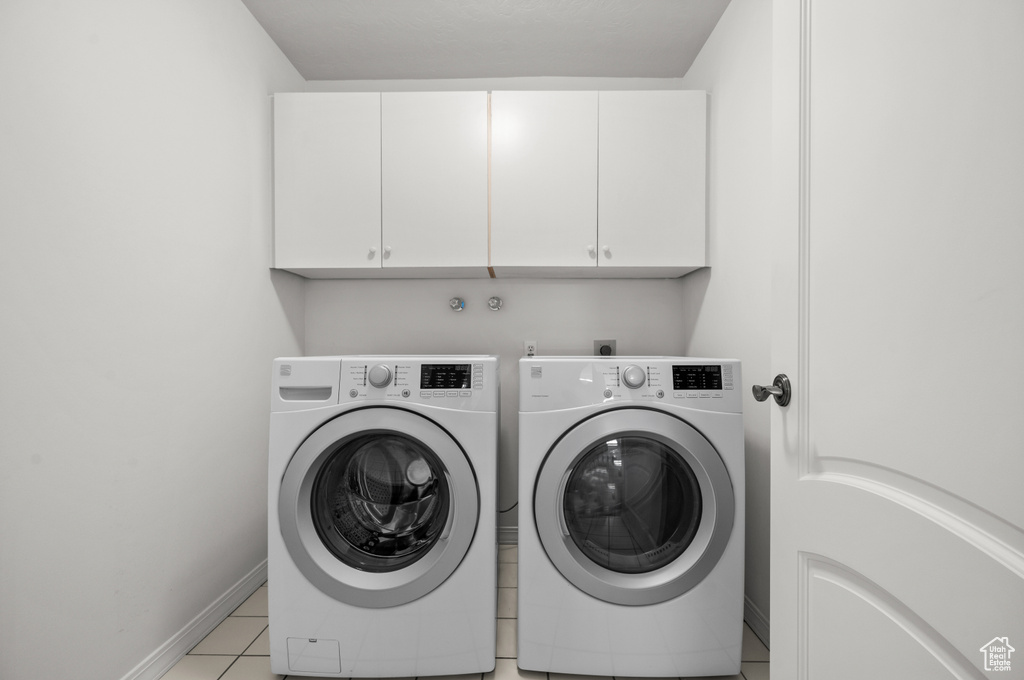 Laundry area with cabinet space, washing machine and dryer, baseboards, and light tile patterned floors
