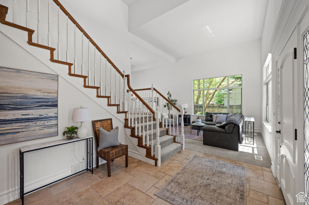 Foyer entrance featuring stone tile floors, stairway, and a high ceiling