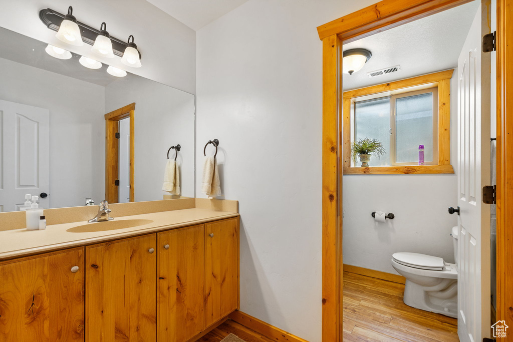 Bathroom with toilet, wood finished floors, vanity, and baseboards