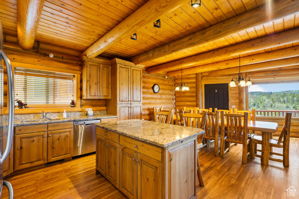 Kitchen featuring stainless steel appliances, rustic walls, light wood-style flooring, a chandelier, and decorative light fixtures