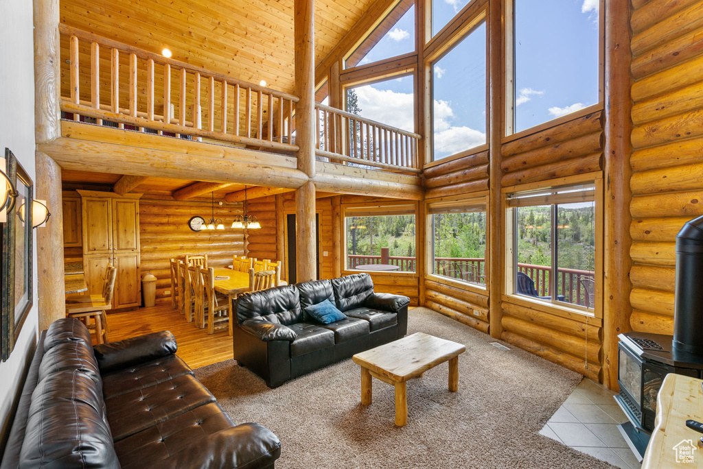 Tiled living area with rustic walls, a wood stove, a high ceiling, plenty of natural light, and a chandelier