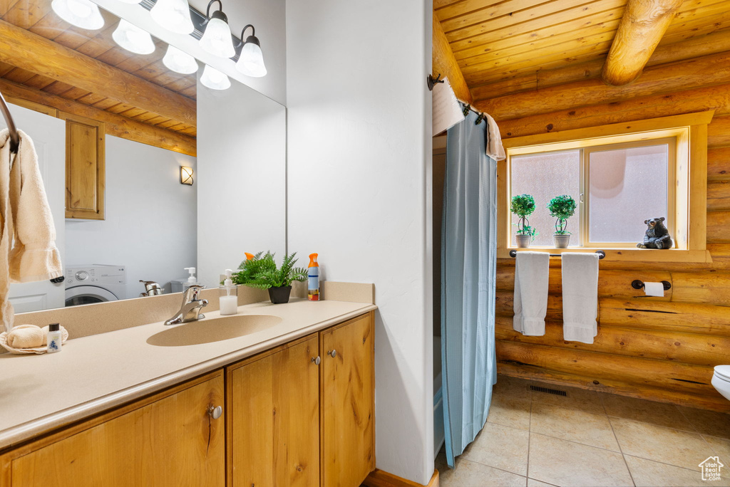 Full bath featuring rustic walls, washer / clothes dryer, vanity, tile patterned floors, and toilet