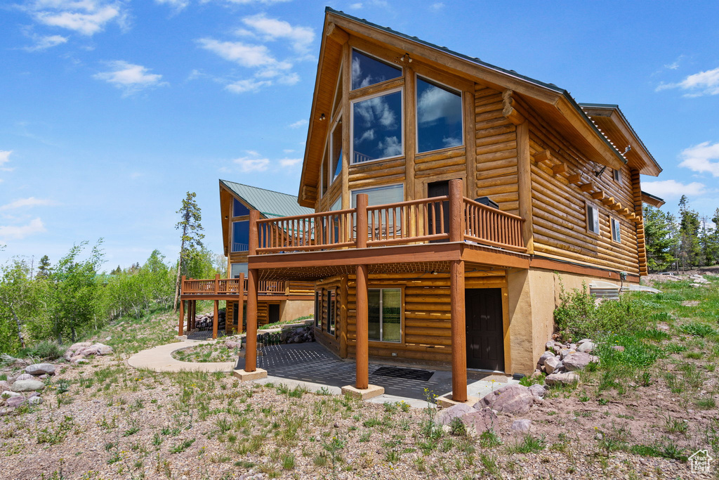 Rear view of house with a wooden deck, log siding, a patio, and stairway