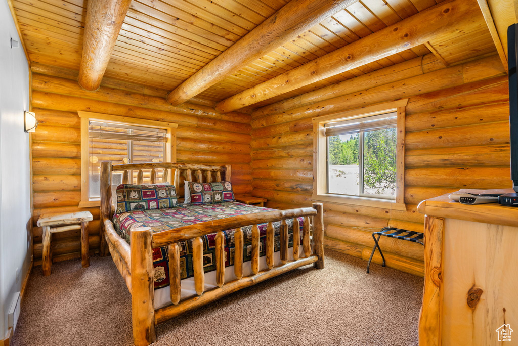 Bedroom with wooden ceiling with exposed beams, carpet floors, and rustic walls