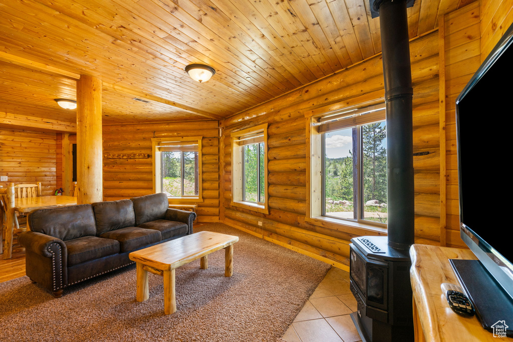 Living room with a wood stove, log walls, wooden ceiling, and light tile patterned floors