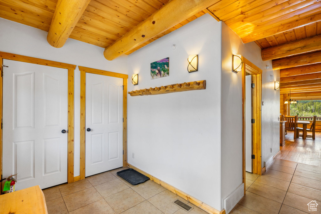 Foyer with wooden ceiling with exposed beams, light tile patterned flooring, and baseboards