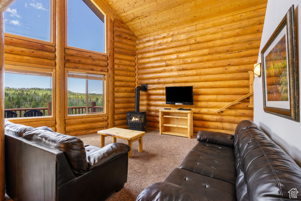Carpeted living area featuring a wood stove, high vaulted ceiling, wooden ceiling, and rustic walls
