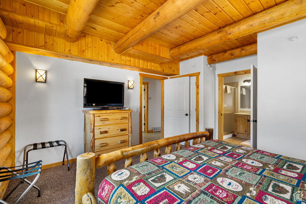 Bedroom with wood ceiling with exposed beams, light carpet, baseboards, and log walls