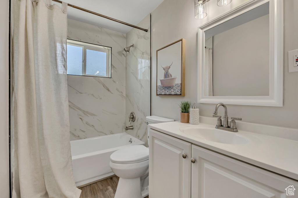 Full bathroom featuring vanity, shower / tub combo, toilet, and wood finished floors