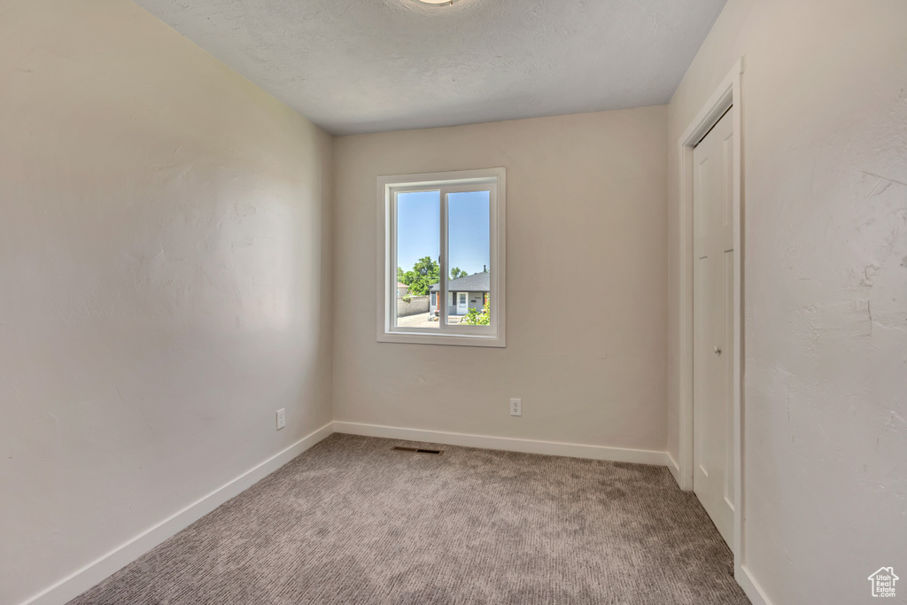 Carpeted spare room with baseboards and a textured ceiling