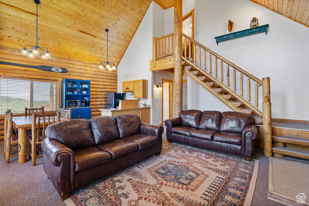 Living room with rustic walls, carpet floors, high vaulted ceiling, wood ceiling, and stairway