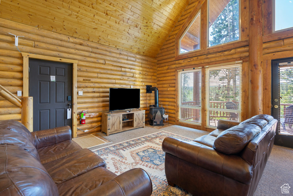 Carpeted living room with high vaulted ceiling, rustic walls, a wood stove, and wooden ceiling