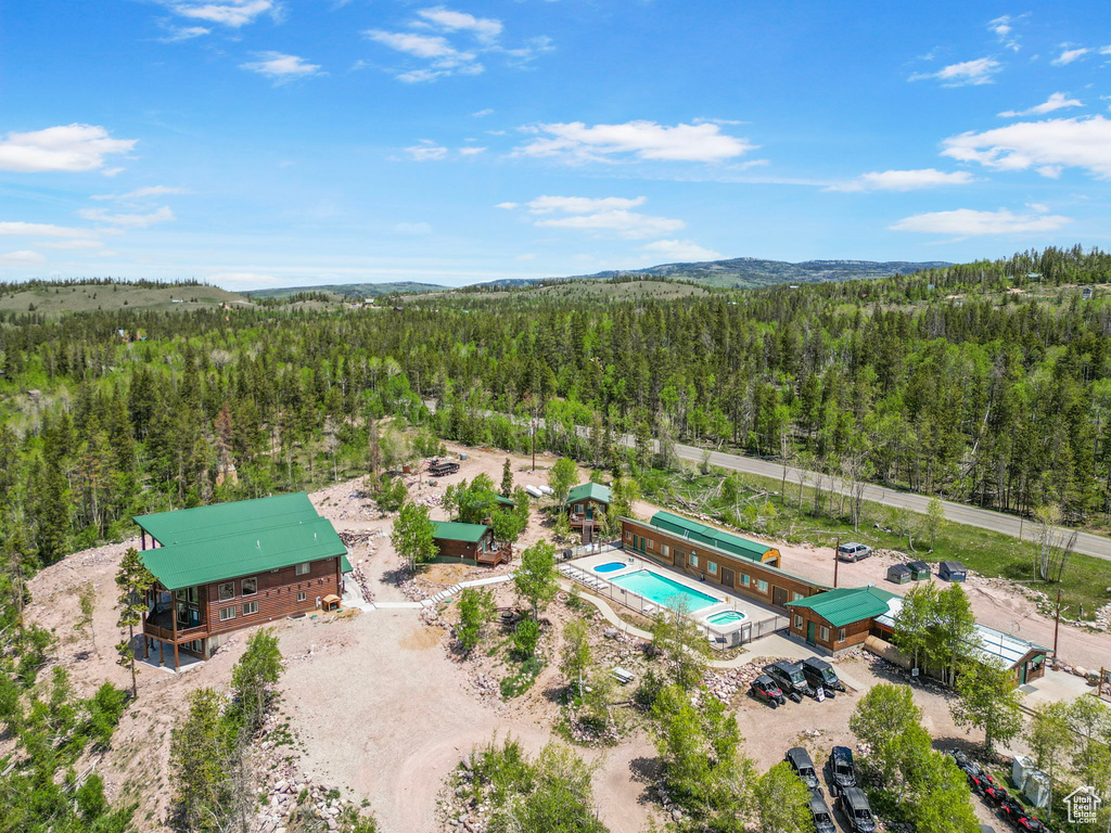Bird\'s eye view of a heavily wooded area, a pool, and a mountain backdrop