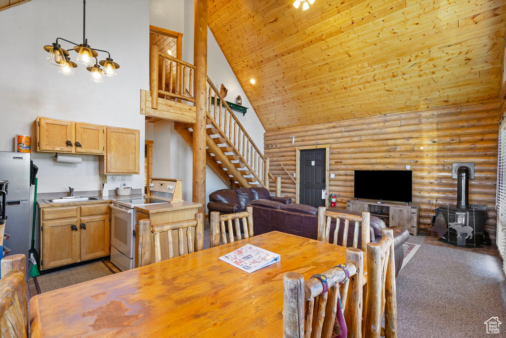 Dining room with high vaulted ceiling, log walls, a wood stove, stairway, and dark colored carpet