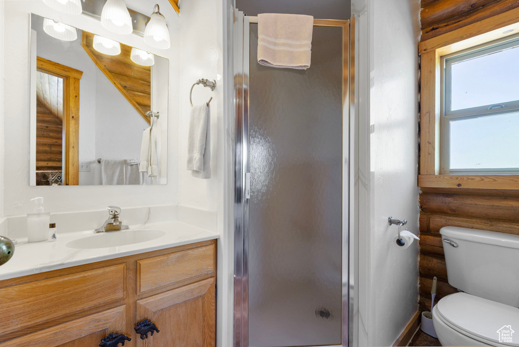 Full bathroom featuring vanity, a shower stall, rustic walls, and toilet