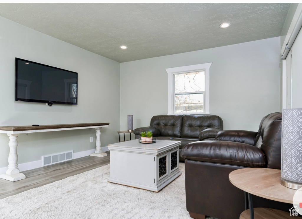 Living area with light wood-type flooring, baseboards, and recessed lighting