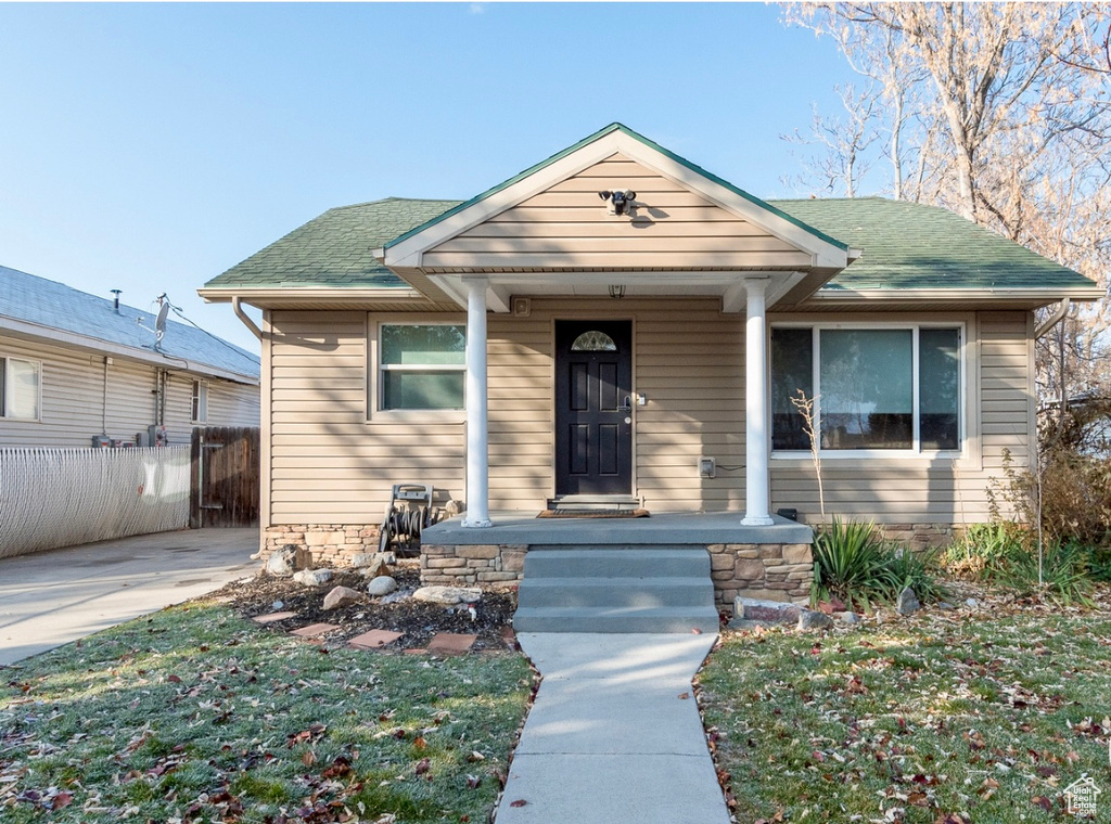 View of front of house featuring roof with shingles and a porch