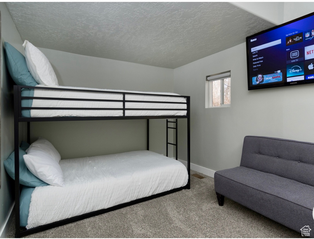 Bedroom with carpet floors, a textured ceiling, and baseboards