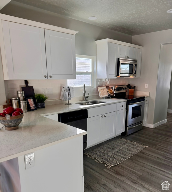 Kitchen featuring stainless steel appliances, a sink, dark wood finished floors, tasteful backsplash, and white cabinets