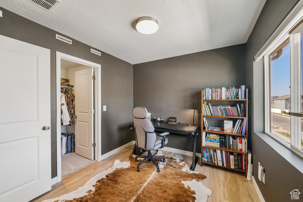 Office area with healthy amount of natural light, wood finished floors, baseboards, and a textured ceiling