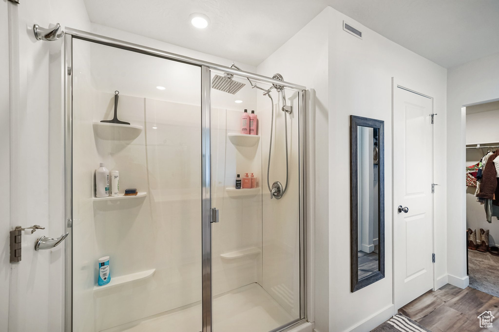 Bathroom with a shower stall, wood finished floors, a spacious closet, baseboards, and recessed lighting