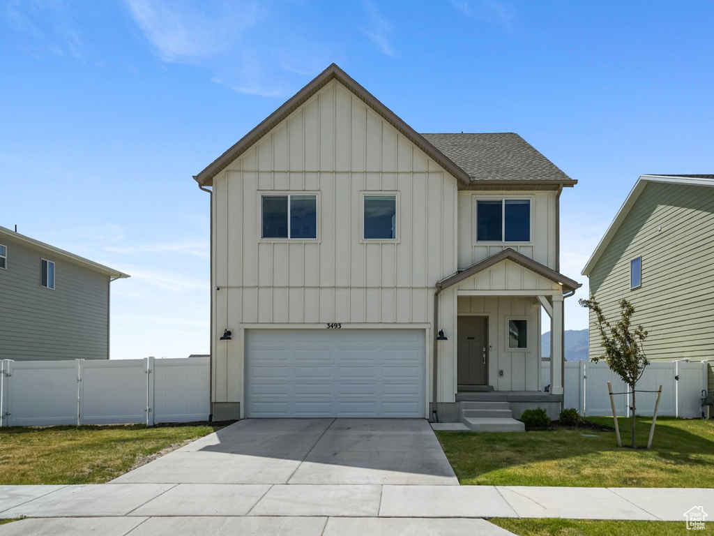 View of front of house with board and batten siding, a gate, an attached garage, and driveway