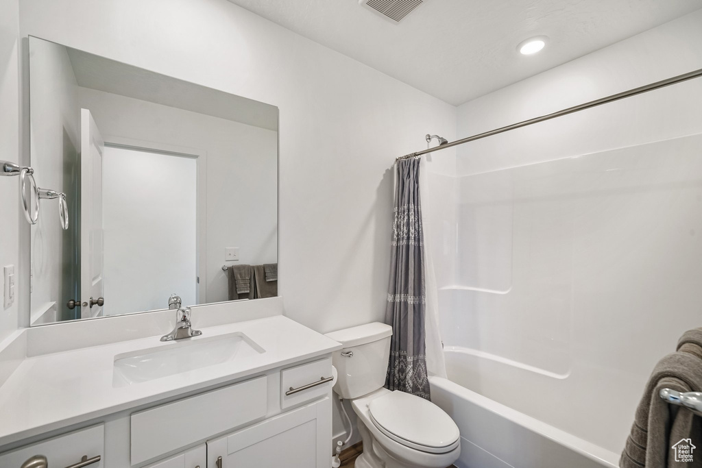 Full bathroom featuring toilet, vanity, and shower / bathtub combination with curtain