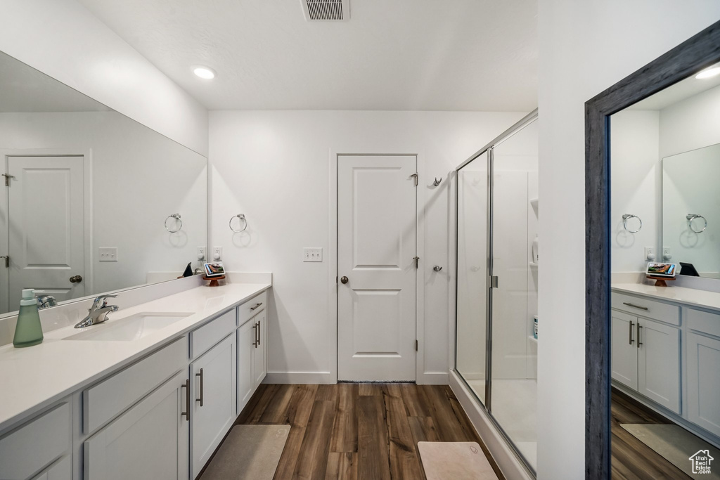 Bathroom with vanity, wood finished floors, a shower stall, and baseboards