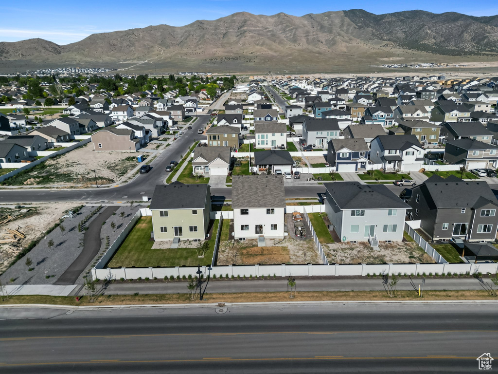Aerial view of property and surrounding area featuring nearby suburban area and a mountain backdrop
