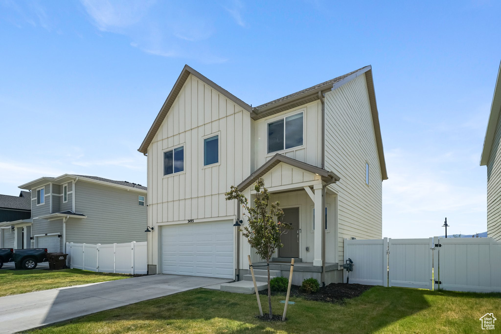 View of front of property featuring board and batten siding, a gate, a garage, and driveway