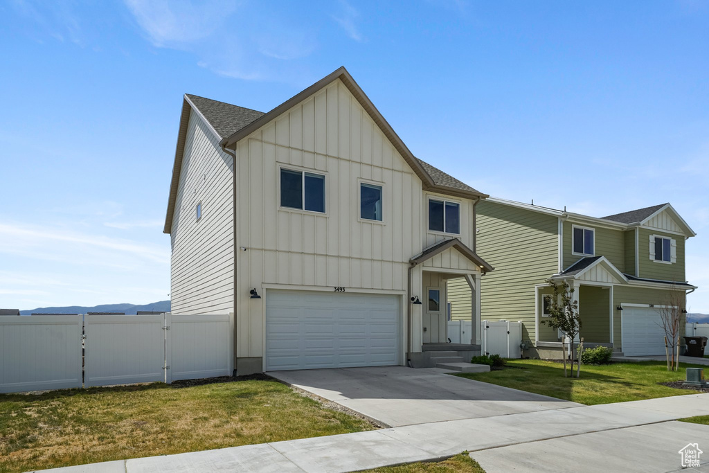 View of front of home featuring board and batten siding, a garage, a gate, driveway, and a shingled roof