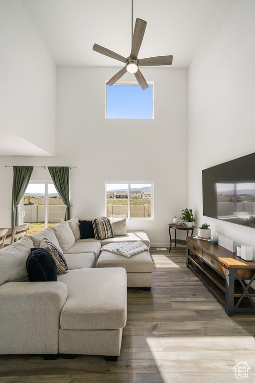 Living room with a high ceiling, ceiling fan, and wood finished floors