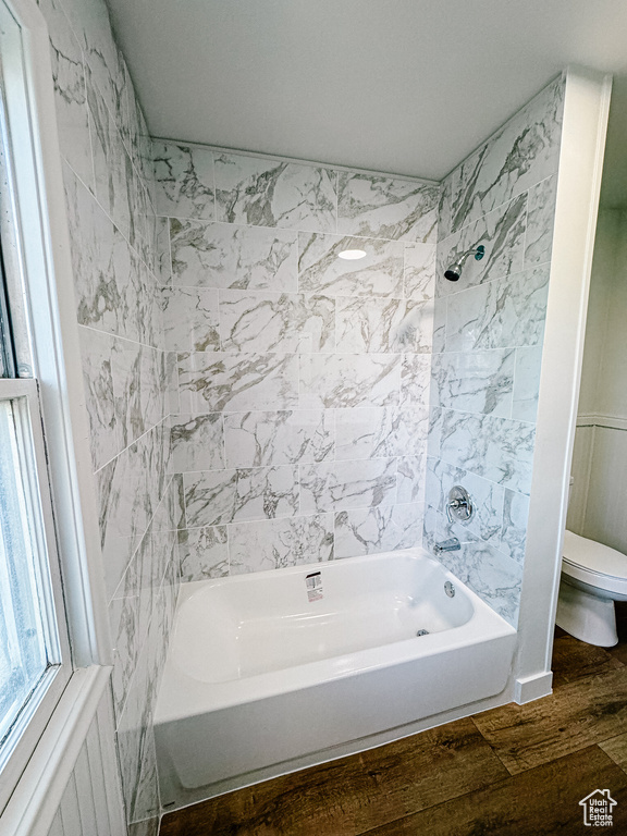 Bathroom featuring toilet, wood finished floors, and  shower combination