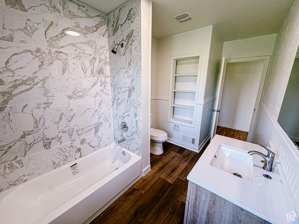 Full bath featuring toilet, wood finished floors, vanity, shower / washtub combination, and built in features