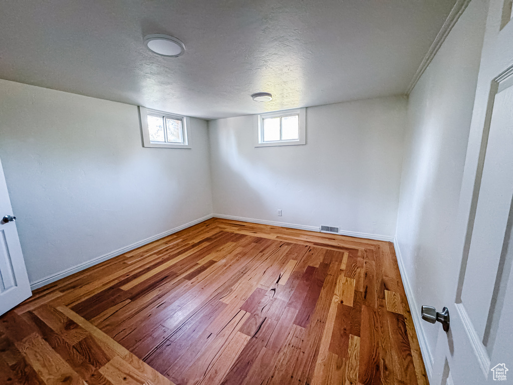 Basement with baseboards, wood finished floors, and a textured ceiling