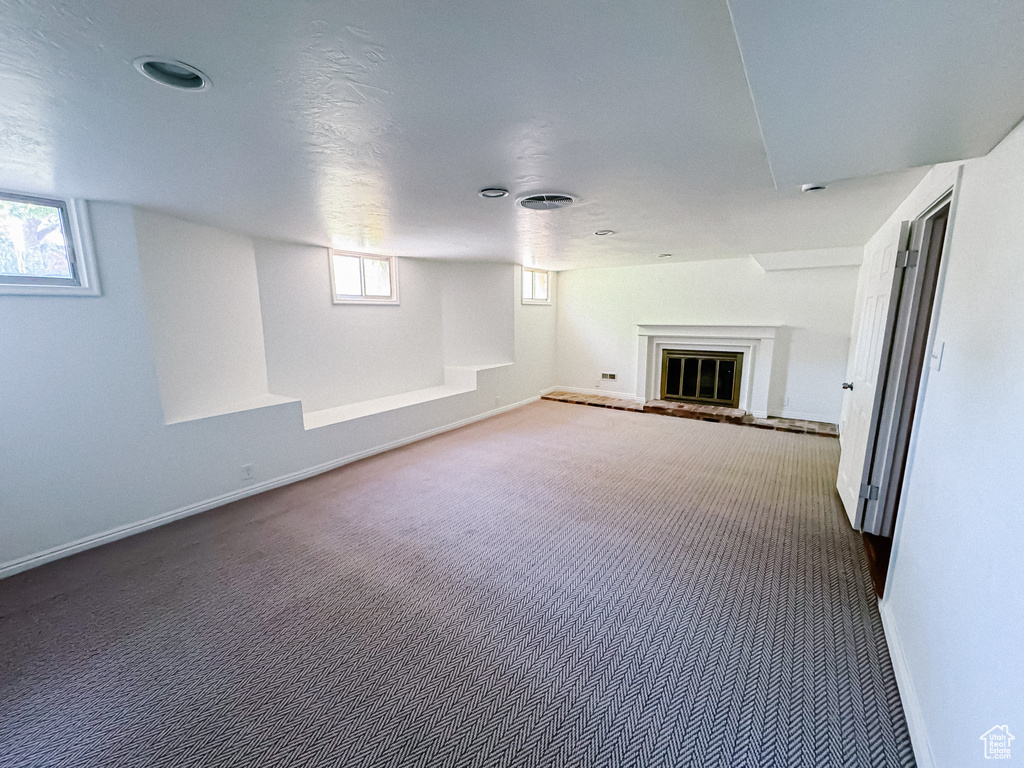 Basement featuring carpet floors, baseboards, and healthy amount of natural light