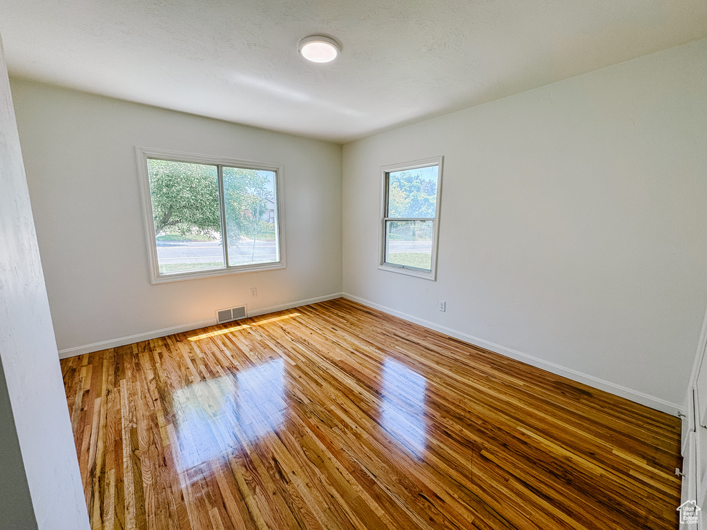 Unfurnished room with healthy amount of natural light, wood finished floors, and baseboards