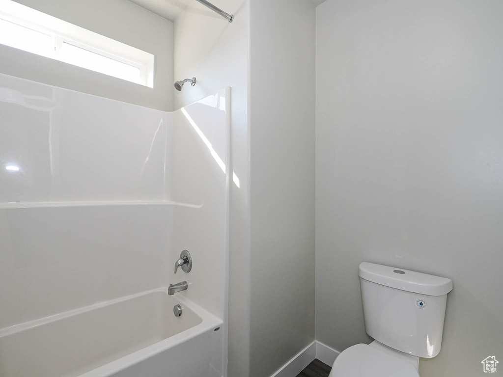 Full bath with shower / washtub combination, toilet, and baseboards